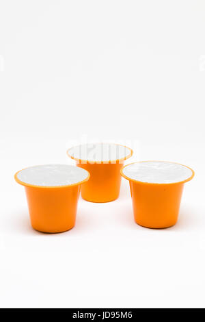 Three isolated Orange Coffee pods on white background Stock Photo