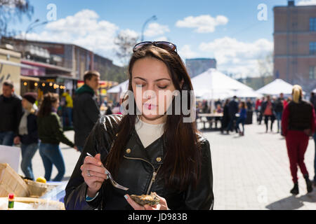 Young woman holding a single fresh opened oyster at outdoor food festival Stock Photo