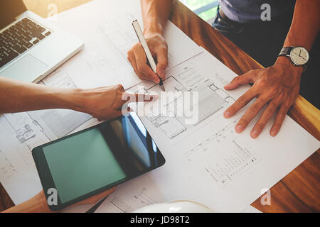 Architects engineer discussing at the table with blueprint - Closeup on hands and project print. Stock Photo