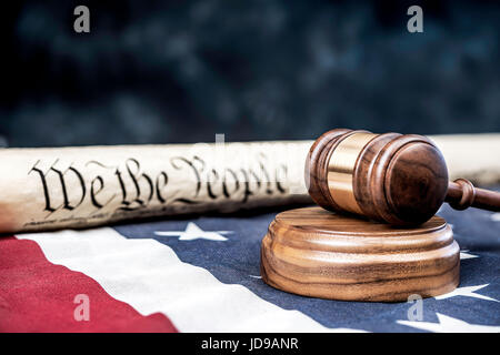The United States Constitution rolled up on an American flag with a gavel in the foreground. Room for copy along the top half of the image. Stock Photo