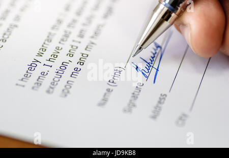 close up of a men hand holding pen and signing papers Stock Photo