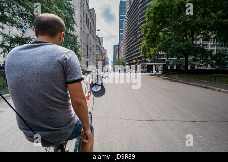 Rear view of man on bicycle on empty street in New York City, New York, USA. 2016 urban city United States of America