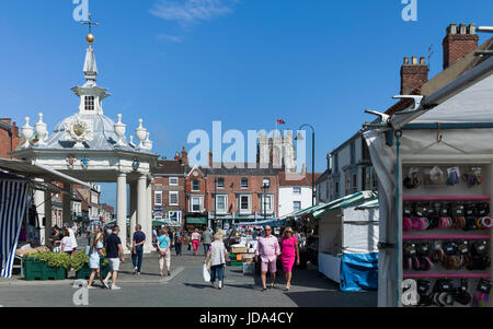 Shoppers enjoy the popular Saturday Market with view of the bandstand and St Mary's Church on a sunny morning in Beverley, Yorkshire, UK. Stock Photo