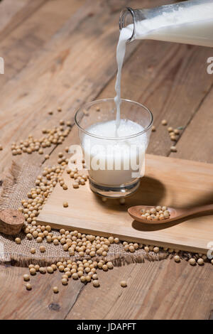Soy milk or soya milk and soy beans in spoon on wooden table. Stock Photo