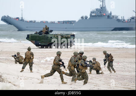 An American Assault Amphibious Vehicle AAV-7 on the beach and Polish minelayer-landing ship ORP Krakow during the 45th edition of Exercise BALTIC OPER Stock Photo