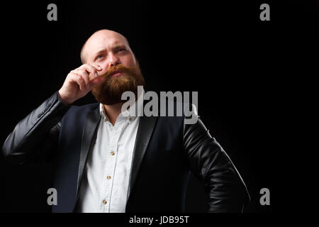 Man in black jacketturns his ginger mustache on blank background Stock Photo