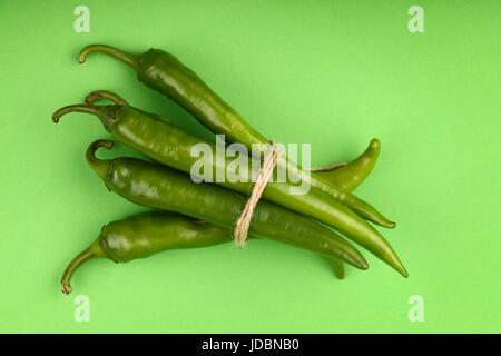 One bunch of fresh jalapeno hot chili peppers with natural twine on green paper background, close up, elevated top view Stock Photo