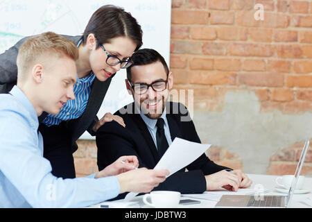Contemporary traders reading papers in office Stock Photo