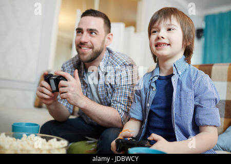 Happy boy and his father playing video game at leisure Stock Photo
