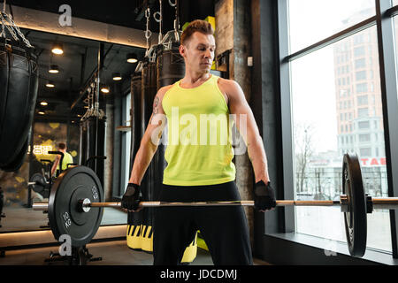 Young concentrated fitness man doing workout with heavy barbell at the gym Stock Photo