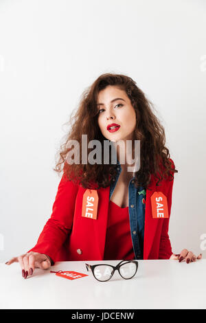 Pretty modern girl wearing clothes with sale signs and looking at camera isolated over white background Stock Photo