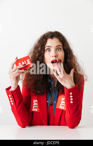 Surprised young shopaholic woman holding sale sign isolated over white background Stock Photo