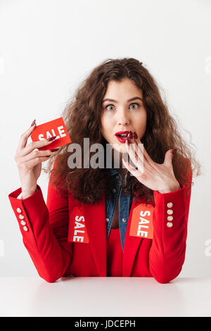 Shocked shopaholic woman holding sale sign isolated over white background Stock Photo