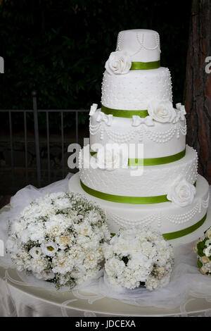 five-tiered white wedding cake covered with white roses and bouquet Stock Photo