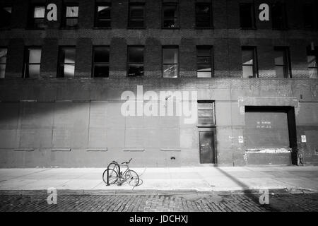 Forgotten bike. Bicycle locked by a street in Dumbo neighborhood at sunset, New York City, USA. Stock Photo