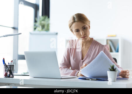 serious businesswoman with laptop and documents working in office Stock Photo