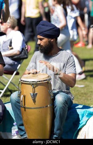 Young man wearing a turban learning to play African Drums at the Africa Oye music festival in Sefton Park Liverpool Stock Photo