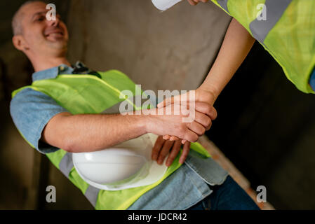 Close-up of a shaking hands of a construction workers in building damaged in the disaster. Stock Photo