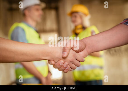 Close-up of a shaking hands of a construction workers in building damaged in the disaster. Selective focus. Stock Photo