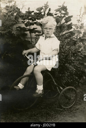 Antique c1930 photograph, six year old boy on a tricycle. Location is probably Minnesota. SOURCE: ORIGINAL PHOTOGRAPH. Stock Photo