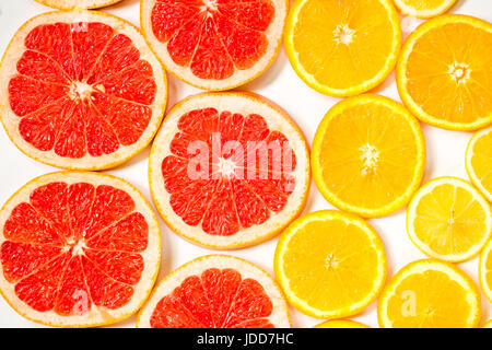 Gradient citrus slices - grapefruit, orange and lemon, placed on white background from left to right, from big to smaller sizes Stock Photo
