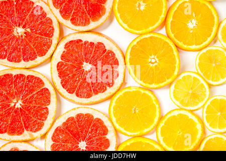 Gradient citrus slices - grapefruit, orange and lemon, placed on white background from left to right, from big to smaller sizes Stock Photo