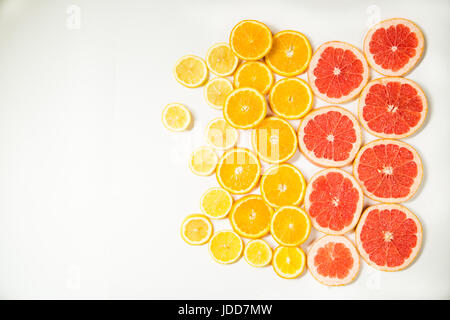 Gradient citrus slices - grapefruit, orange and lemon, placed on white background from left to right, from big to smaller sizes Stock Photo