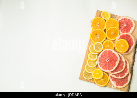 Vitamin C fruits - lemon, orange and grapefruits slices on woden cutting board on white background Stock Photo