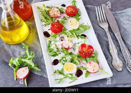 Fresh radish, cherry tomato, quail egg, ruccola with balsamic glaze on a white plate. Mediterranean lifestyle. Healthy food. Stock Photo