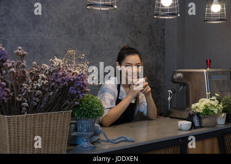 small business owner at her coffee shop. happy asian woman standing at the counter. young female barista smiling behind the bar in cafe Stock Photo