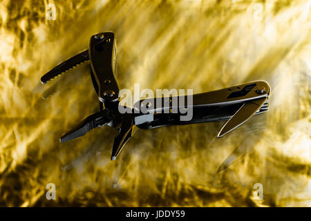 black steel folding multitool on golden background Stock Photo