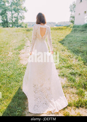 The full-length back view of the bride in the stylish long wedding dress Stock Photo