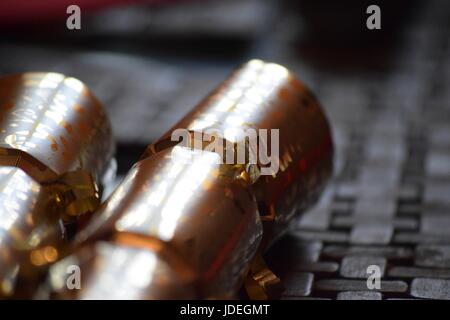 Two gold Christmas Crackers on a wooden place mat. Stock Photo