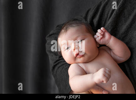 Newborn baby on a black background.  Baby resting in mother's hand. Newborn concept and the concept of a young family Stock Photo