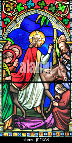 Story of Easter, Entry into Jerusalem, Jesus rides on a donkey, crowds welcome him, spread clothes before him, Palm Sunday, stained glass window Stock Photo