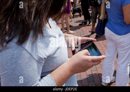 Woman using tablet PC in a crowd - USA Stock Photo