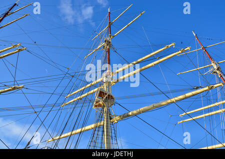 Crows nest, mast, and canvas sails can be seen in this closeup detail of an old time tall wooden sailing ship. Stock Photo