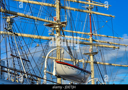 Crows nest, mast, and canvas sails can be seen in this closeup detail of an old time tall wooden sailing ship. Stock Photo