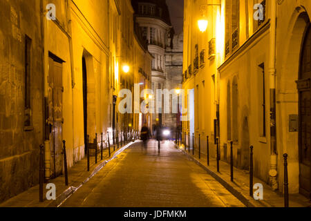 Two women walk in blurry motion at night on one of the streets of Le Marais district in Paris. It's night time. The district hosts many outstanding bu Stock Photo
