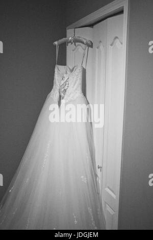 wedding dress of bride hanging on door Stock Photo