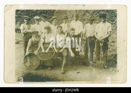 Early 1900's Edwardian historical postcard photo of young men working in a quarry holding sieves possibly used for screening aggregates into the required sizes, possibly for road building or construction, builder builders - also with tools and shovels, circa 1905, UK Stock Photo