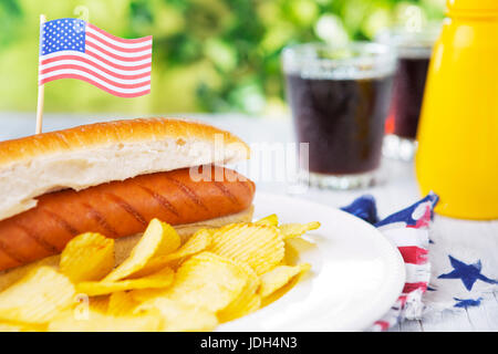 A tasty hot dog with potato chips on an outdoor table. Stock Photo