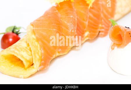 Scrambled eggs with cheese and salmon decorated with tomato on white background Stock Photo