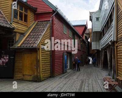 Tourists in Jacobsfjorden and Bellgarden with Hanseatic commercial wooden buildings on each side of passageway Bryggen Bergen Norway UNESCO world Heri Stock Photo