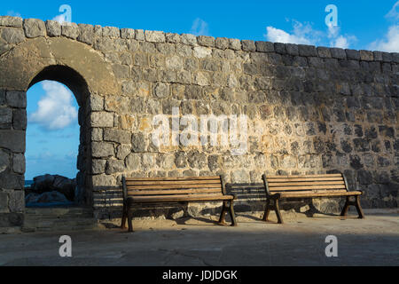 Vintage color tone style of wooden bench antique with sunrise by old city stone wall in Cefalu, Italy Stock Photo