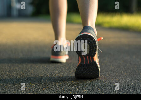 Runner with running shoes on tarmac from behind during sunset Stock Photo