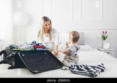 Travelling with kids. Happy mother with her child packing clothes for their holiday Stock Photo