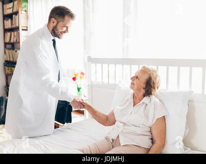 Providing care and support for elderly. Doctor visiting elderly patient at home. Stock Photo