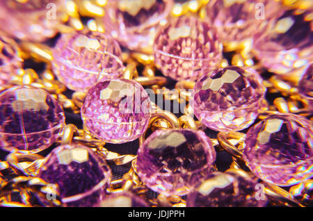 Purple jewelry texture with golden chains. Plastic jewelry, very colorful. Stock Photo