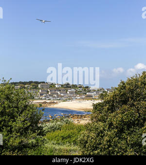 A plane coming in to land at St. Mary's airport over Porthcressa beach and Bay Hugh Town, St. Mary's Island, Isles of Scilly, Cornwall, England, UK Stock Photo